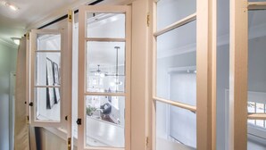 A hallway with open French doors leading to a room with a ceiling fan and a view of the outside. - Charming 2BR in Historic Savannah! (Savannah)
