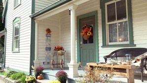 A white house with green trim, a porch with a table and chairs, and a door with a wreath. - Bristow's Inn (Township of Woolwich)