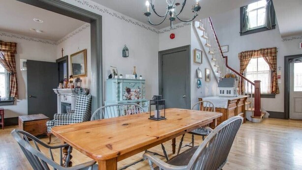 A dining room with a wooden table and metal chairs, a staircase, and a view of the outside. - Bristow's Inn (Township of Woolwich)