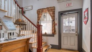 A staircase with a wooden handrail and a white wall with a door marked "EXIT". - Bristow's Inn (Township of Woolwich)