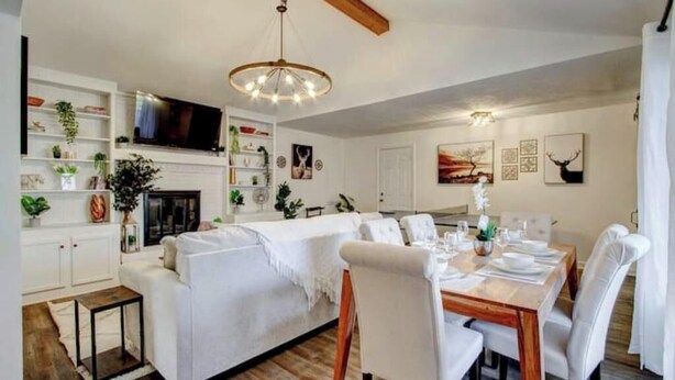 A modern living room with a white sofa, dining table set for four, and a fireplace. - Single-Story Charmer! 5BR! Pet Friendly Getaway

 (Indianapolis)