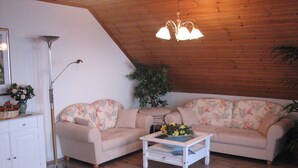 A living room with a sofa, a coffee table, a lamp, and a plant. - Haus Jägerwinkel - Wohnung II (Müllheim im Markgräflerland)