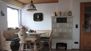 A dining area with a wooden table and chairs, a bench, a chandelier, and a fireplace. - Haus Jägerwinkel - Wohnung II (Müllheim im Markgräflerland)