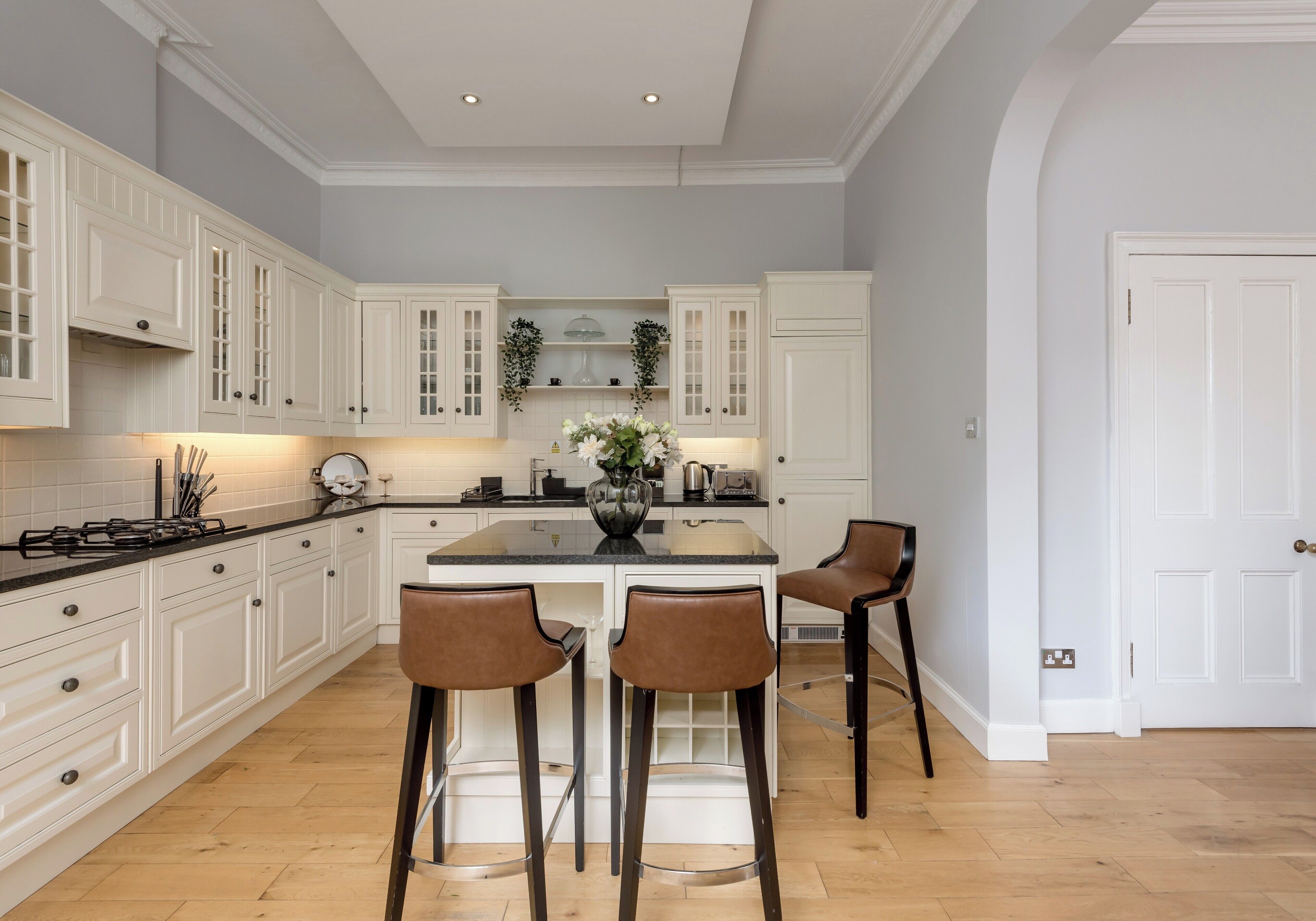 A kitchen with white cabinetry, a central island with chairs, and a stove.