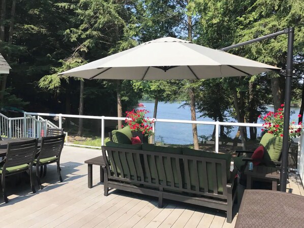 Une terrasse dotée de mobilier d’extérieur, comprenant un banc et des chaises, ainsi qu’un grand parasol pour créer de l’ombre.