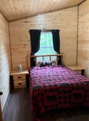 Cozy cabin with a bed, bedside table, and window.