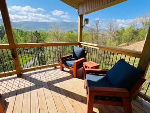 A wooden deck with two chairs and a small table, overlooking a mountainous landscape. - A Tyme to Chill (Sevierville)