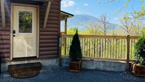 A wooden cabin with a beige door, a small porch, and a view of mountains. - A Tyme to Chill (Sevierville)