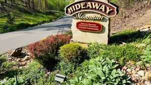 A sign for Hideaway Mountain, a gated community with a road leading through a forested area. - A Tyme to Chill (Sevierville)