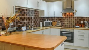 Una cocina moderna con armarios blancos, encimera de madera, pileta de acero inoxidable, microondas, tostadora y estufa.