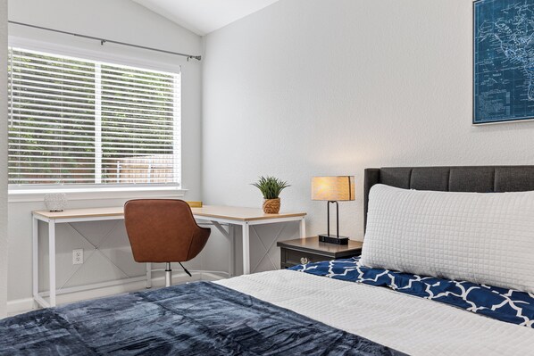 Ein ordentlich eingerichtetes Schlafzimmer mit Bett, Schreibtisch, Stuhl und Nachttisch.