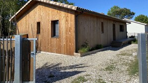 Een houten chalet met schuin dak, een klein terras en een oprit van grind.
