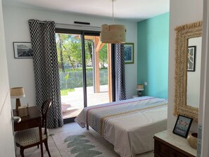 A bedroom with a bed, a desk, a chair, a lamp, and a large mirror. - 143 - charming new timber-framed house for 8 people (HOURTIN)