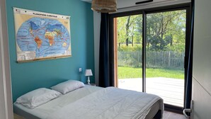 Een slaapkamer met een bed, een kaart aan de muur, een raam en uitzicht op de omgeving.