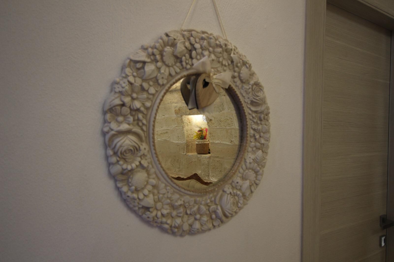 A wall-mounted decorative mirror with an ornate frame featuring floral and shell designs.
