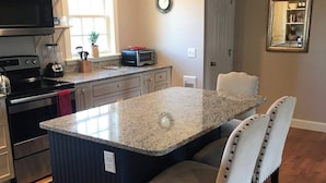 A kitchen with a central island, dark cabinetry, and a dining area with two chairs.