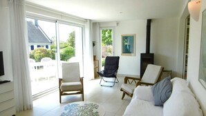 A spacious living room with a white sofa, two armchairs, a coffee table, and a fireplace.