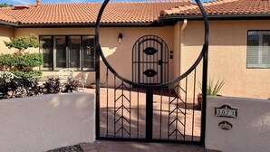Une maison avec un toit recouvert de tuiles rouges, un portail en métal noir et un panneau indiquant le numéro « 1073 » sur le mur.