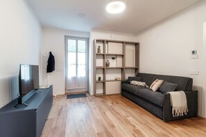 Una sala de estar moderna con un sofá gris, suelo de madera, un mueble para televisión y una estantería empotrada.