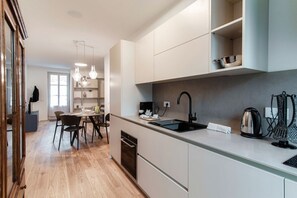 Una cocina moderna con lavavajillas incorporado, un fregadero y una tetera.