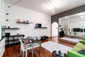 Una cocina moderna con comedor, un sofá verde y un espejo grande que refleja la cocina.
