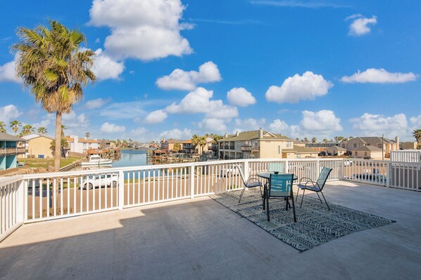 A balcony with a view of a marina, palm trees, and residential buildings.