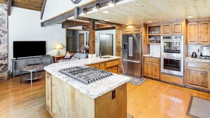 Una cocina amplia con una isla grande, armarios de madera, electrodomésticos de acero inoxidable y una pared de acento de piedra.