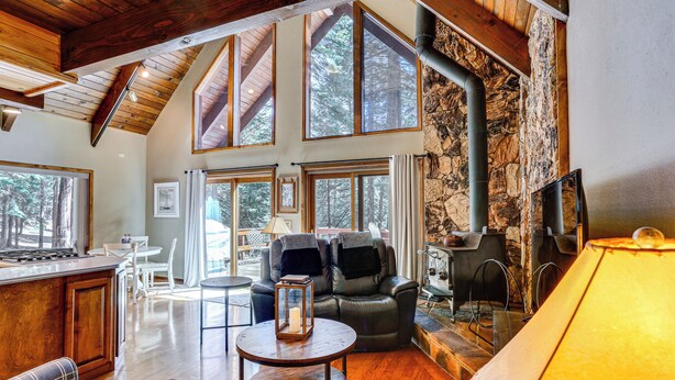 Amplia sala de estar con chimenea, asientos de cuero y grandes ventanas que ofrecen vistas al exterior.