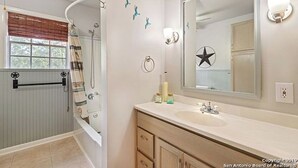 Un baño con bañera, un espejo grande y un tocador con lavamanos.
