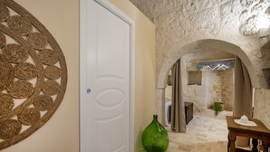A room with a white door, a green vase, and a wooden table. - GuestHost - Beautiful trullo with typical and evocative architecture, equipped with every comfort to accommodate up to 6 people with great comfort in 100 m2, with 2 bedrooms and 2 bathrooms. The accommodation is located in the countryside of the Itria Va (Martina Franca)