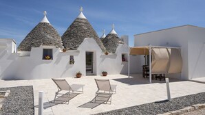 A white building with conical roofs, outdoor seating, and potted plants. - GuestHost - Beautiful trullo with typical and evocative architecture, equipped with every comfort to accommodate up to 6 people with great comfort in 100 m2, with 2 bedrooms and 2 bathrooms. The accommodation is located in the countryside of the Itria Va (Martina Franca)