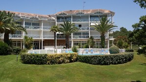 A multi-story hotel with a pool, palm trees, and a well-maintained lawn. - Logement à 700m de la plage, sur le golf Moliets ! (Moliets)