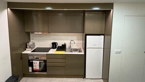 A compact kitchen with a built-in oven, a sink, and a refrigerator. - Refugio do Principe Real (Lisboa)