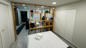 A bedroom with a bed, a wooden shelf with plants, a desk, and a wardrobe. - Refugio do Principe Real (Lisboa)