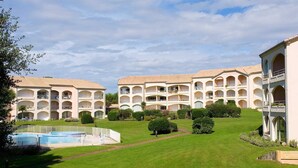 Ein Hotel mit mehreren Balkonen, einem Schwimmbad und gepflegten Rasenflächen.