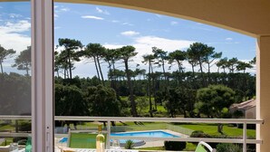 Ein Balkon mit Blick auf einen Pool, Sitzgelegenheiten im Freien und einer Wasserflasche.