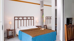 Een slaapkamer met een bed, nachtkastjes, een spiegel en een kledingkast.