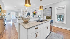 A modern kitchen with white cabinetry, granite countertops, and gold pendant lighting. - 🦩Book Me Baby! Ain't Life Grand 30A~GolfCart~6bikes🦩 (Santa Rosa Beach)