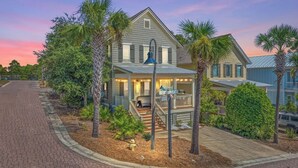 A two-story house with a porch, a front yard with palm trees, and a street view. - 🦩Book Me Baby! Ain't Life Grand 30A~GolfCart~6bikes🦩 (Santa Rosa Beach)