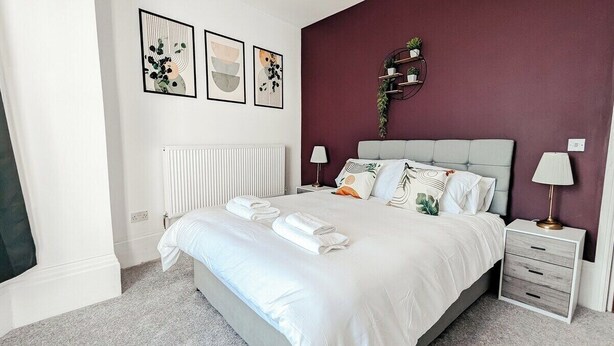 Ein Schlafzimmer mit Bett, Nachttischen, Heizkörper und Wandbildern.