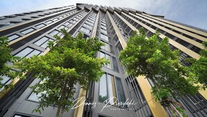 A modern high-rise building with multiple floors, large windows, and some greenery in the foreground. - The EDGE (Pattaya)