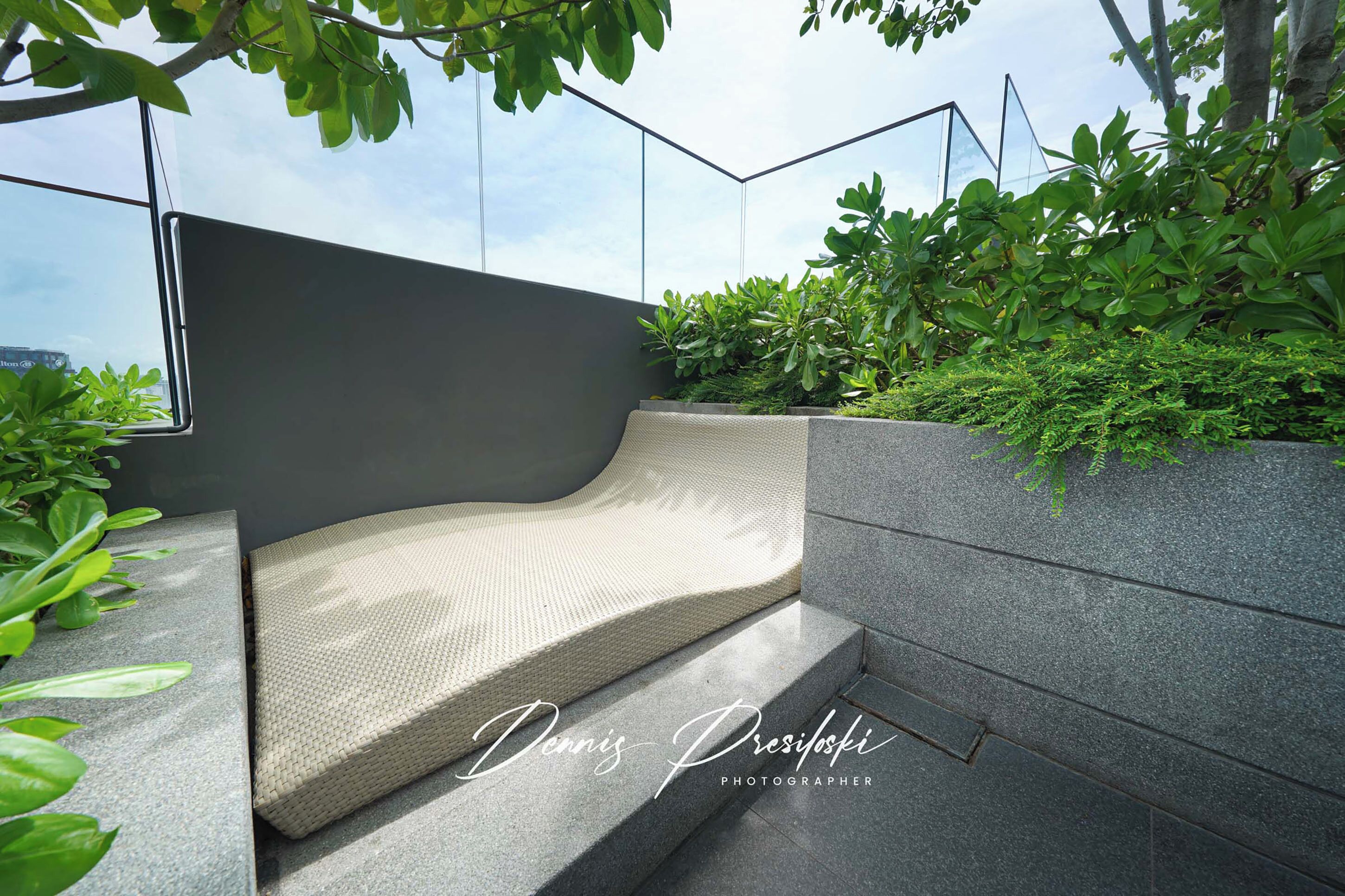 A modern outdoor seating area with a curved bench and a stone wall.