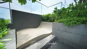 A modern outdoor seating area with a curved bench and a stone wall.