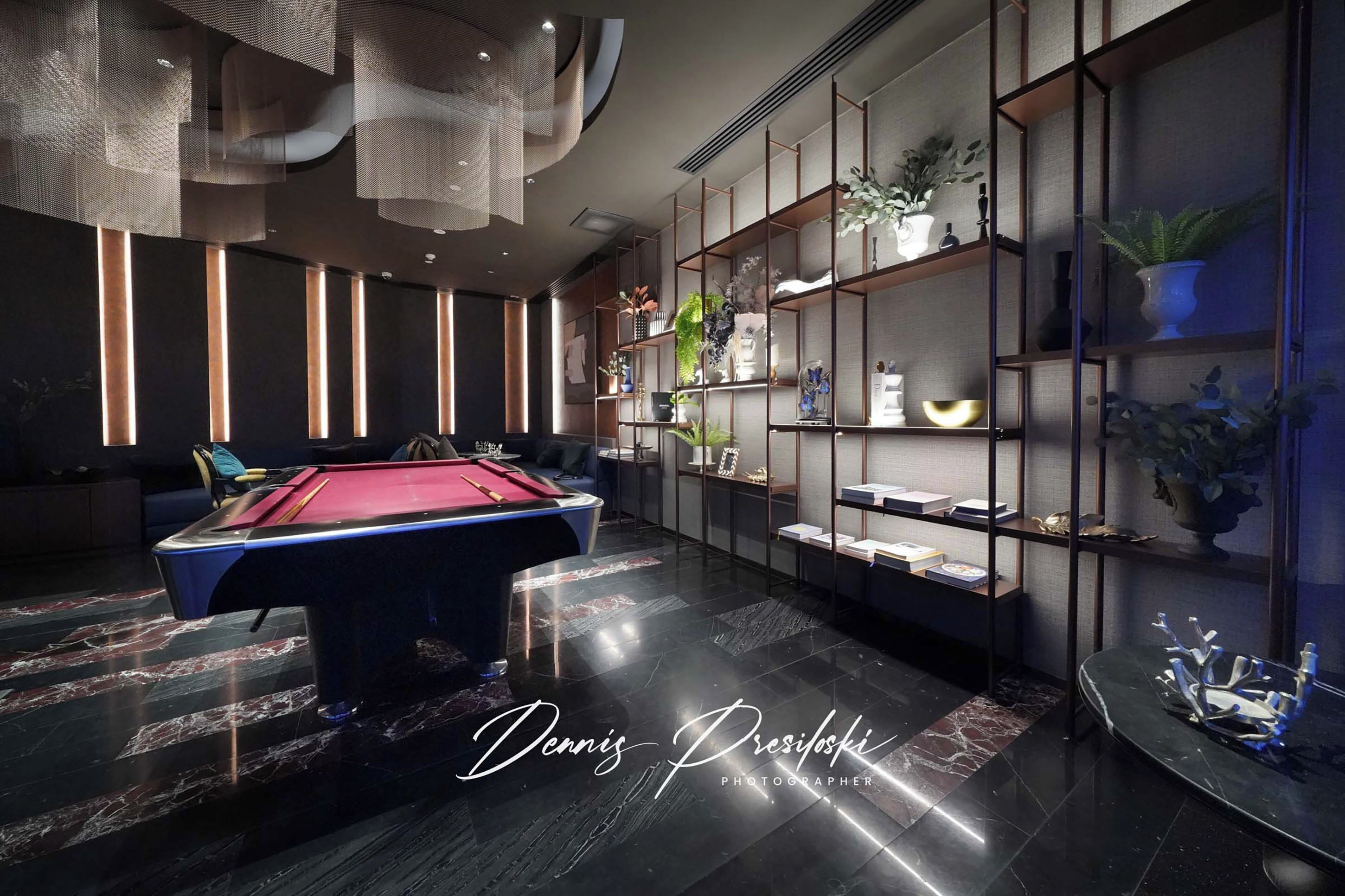 A modern lounge area with a pool table, shelves with decorative items, and a seating area.