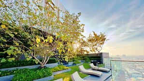 A rooftop terrace with lounge chairs and a view of the city. - The EDGE (Pattaya)