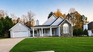 Une maison à deux étages avec un garage, une véranda et un mur d’accent en pierre.