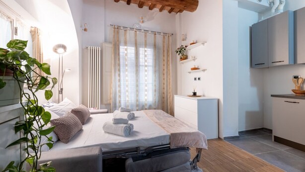 Un dormitorio moderno con cama, mesita de noche y vistas a la cocina.