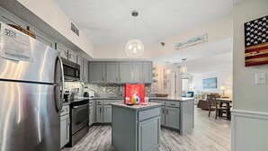 Une cuisine moderne avec des meubles gris, des appareils en acier inoxydable et un îlot central.