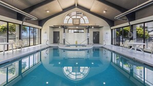 Une piscine intérieure moderne, dotée d’un haut plafond, de grandes fenêtres et d’espaces aménagés pour se détendre.