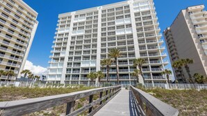 Un hôtel à plusieurs étages, doté de balcons et d’une promenade en bois menant à l’entrée.